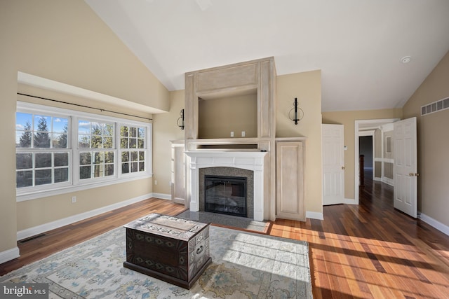 living area with a fireplace with flush hearth, visible vents, baseboards, and wood finished floors