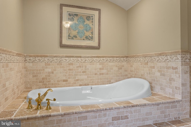 full bathroom featuring a garden tub and a wainscoted wall