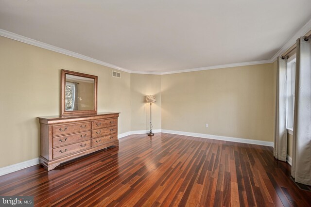 spare room featuring dark wood-type flooring, visible vents, baseboards, and crown molding