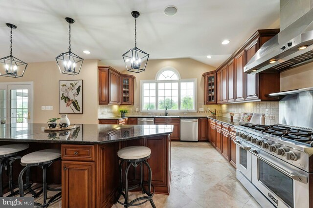 18102 Eaglesham Ct, Leesburg, VA 20175 - kitchen featuring wall chimney range hood, stainless steel appliances, a breakfast bar, brown cabinetry, and backsplash