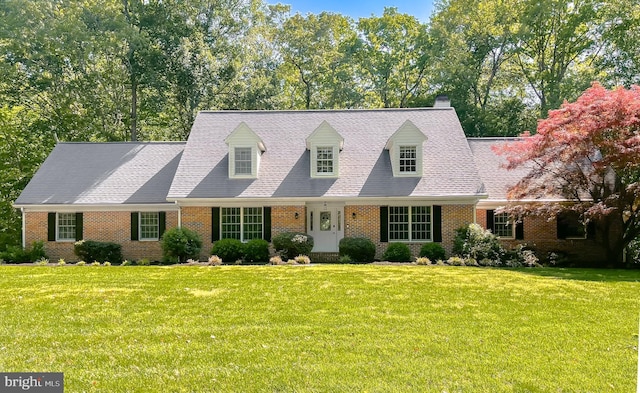 cape cod home with a chimney, a front lawn, and brick siding