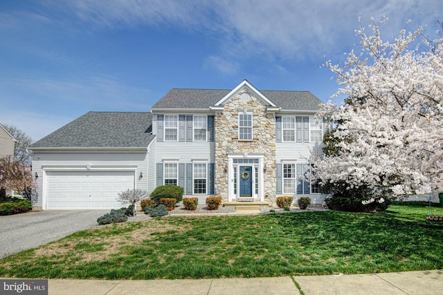 24 W Shakespeare Dr, Middletown, DE 19709 - colonial house featuring asphalt driveway, stone siding, a garage, a front lawn, and a shingled roof