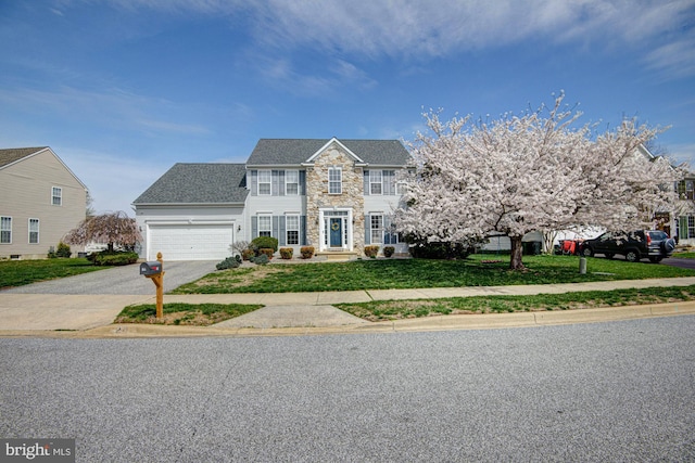 24 W Shakespeare Dr, Middletown, DE 19709 - colonial-style house with asphalt driveway, stone siding, a front lawn, and a garage
