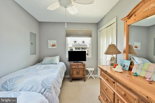 bedroom featuring a ceiling fan, a closet, electric panel, light colored carpet, and baseboards