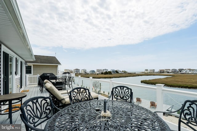 wooden deck with grilling area, a water view, and outdoor dining space