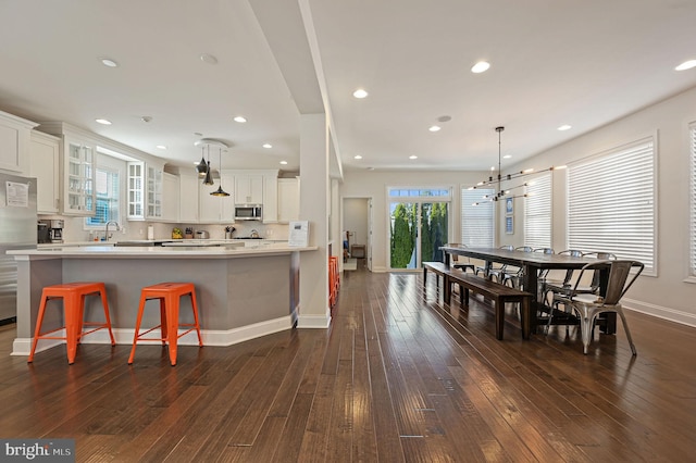 kitchen featuring white cabinets, stainless steel appliances, glass insert cabinets, and dark wood finished floors