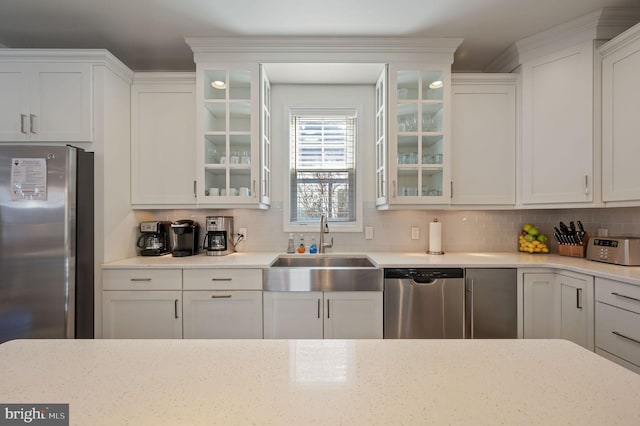 kitchen with a sink, backsplash, white cabinets, and appliances with stainless steel finishes