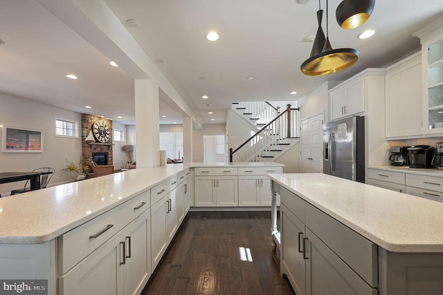 kitchen with stainless steel fridge, dark wood-type flooring, glass insert cabinets, and recessed lighting