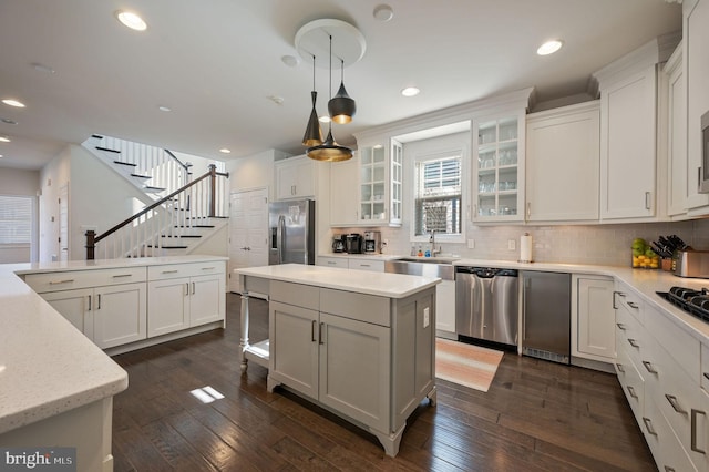 kitchen featuring tasteful backsplash, stainless steel appliances, dark wood finished floors, a kitchen island, and white cabinets