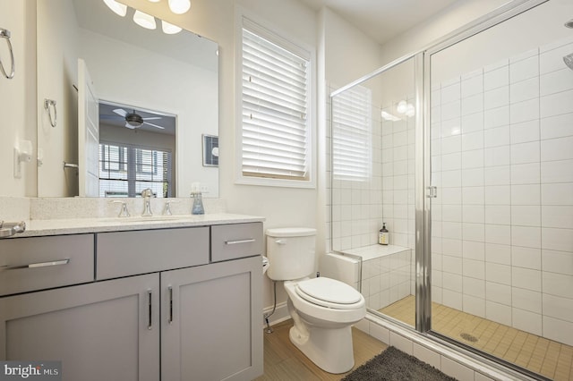 bathroom featuring a ceiling fan, toilet, a stall shower, and vanity