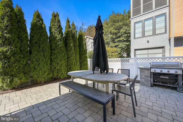 view of patio with grilling area, outdoor dining area, and fence