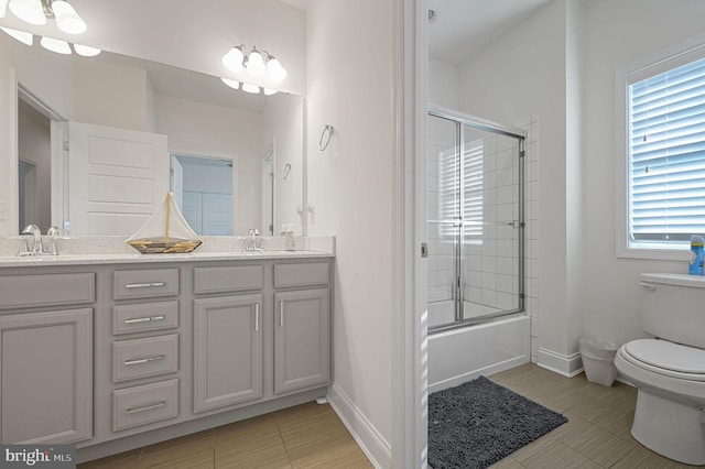 bathroom featuring double vanity, toilet, baseboards, and a sink
