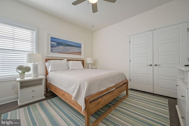 bedroom featuring baseboards, a closet, wood finished floors, and a ceiling fan