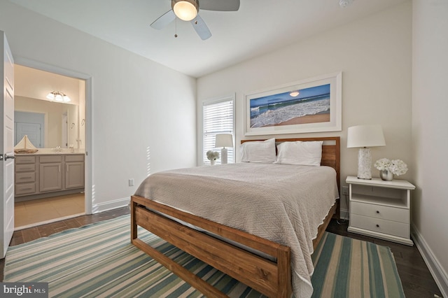 bedroom featuring baseboards, wood finished floors, ceiling fan, and ensuite bath