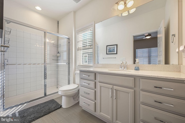 bathroom featuring vanity, toilet, tile patterned floors, a stall shower, and a ceiling fan