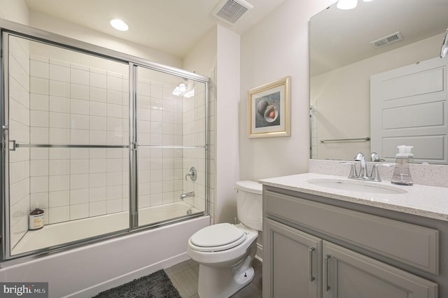 bathroom with visible vents, toilet, vanity, and shower / bath combination with glass door
