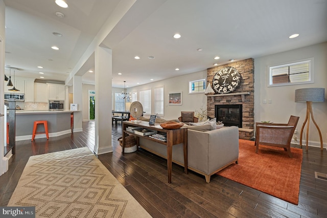living room with baseboards, a fireplace, recessed lighting, dark wood finished floors, and a notable chandelier