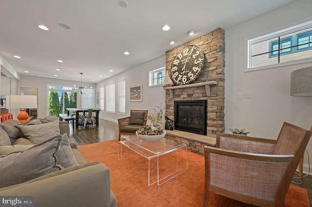 living area featuring a notable chandelier, a fireplace, wood finished floors, baseboards, and recessed lighting