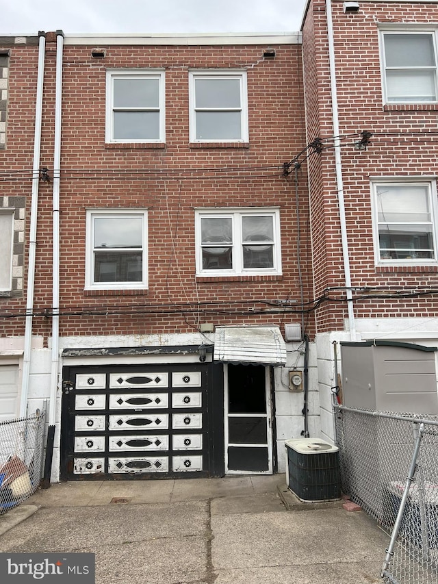 multi unit property featuring cooling unit, fence, and brick siding