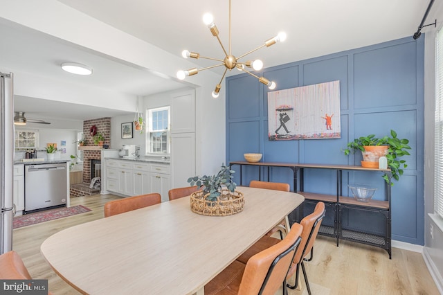 219 Hitching Post Dr, Bel Air, MD 21014 - dining space with light wood finished floors, a brick fireplace, a decorative wall, a chandelier, and a ceiling fan