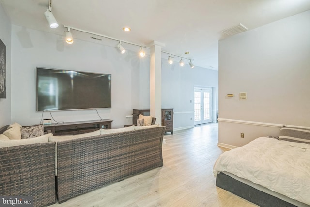 bedroom with baseboards, rail lighting, wood finished floors, and visible vents