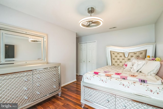 bedroom featuring baseboards, a closet, wood finished floors, and visible vents