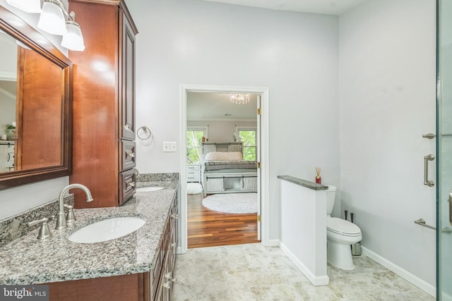 bathroom with toilet, double vanity, baseboards, and a sink