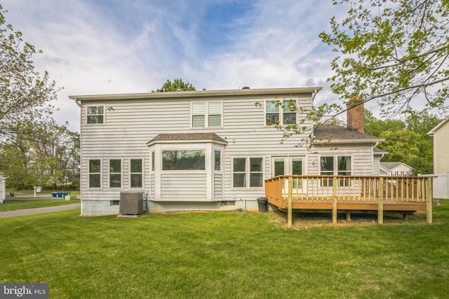 rear view of property with a lawn, a chimney, a deck, and cooling unit