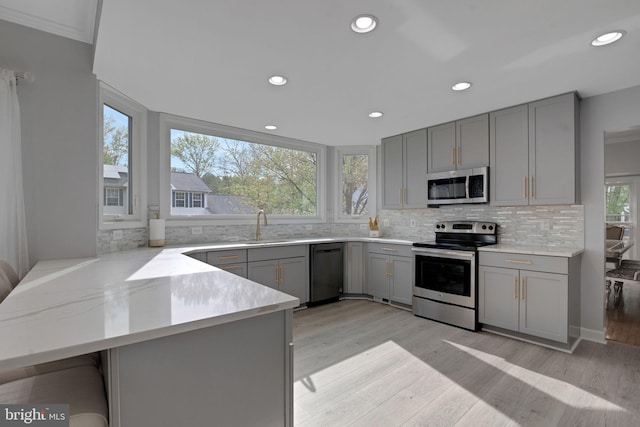 kitchen featuring appliances with stainless steel finishes, a sink, gray cabinets, recessed lighting, and decorative backsplash