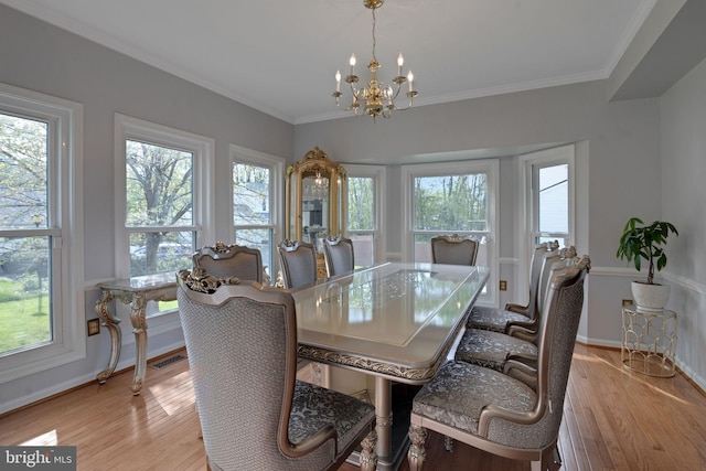 dining space with light wood-style floors, baseboards, crown molding, and a chandelier