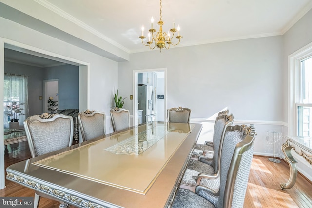 dining space with an inviting chandelier, ornamental molding, and wood finished floors