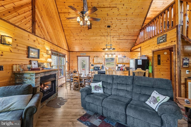living room featuring wood ceiling, a ceiling fan, a fireplace, wood finished floors, and wooden walls