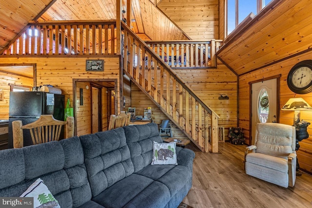 living area with wooden walls, high vaulted ceiling, wood ceiling, and wood finished floors