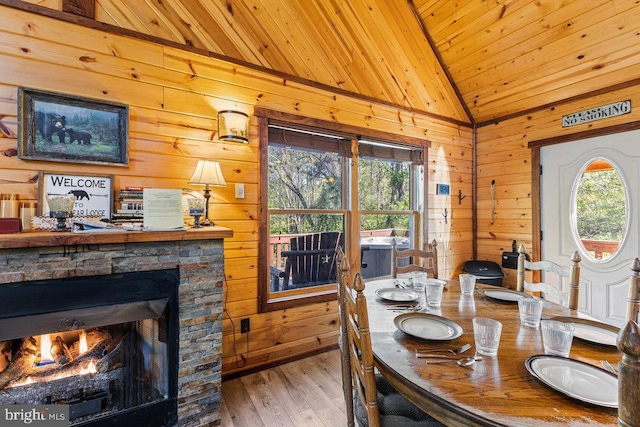 dining space featuring wooden walls, wood finished floors, vaulted ceiling, and wooden ceiling