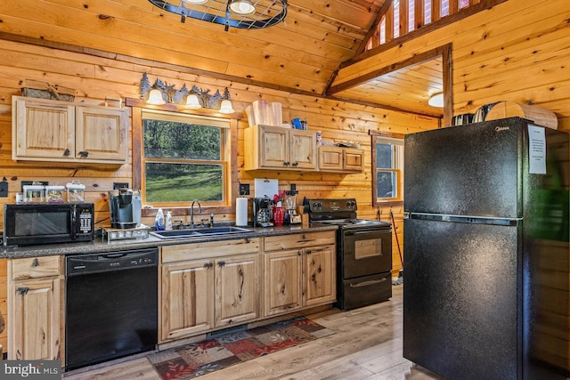 kitchen with dark countertops, wood walls, a sink, black appliances, and light wood finished floors