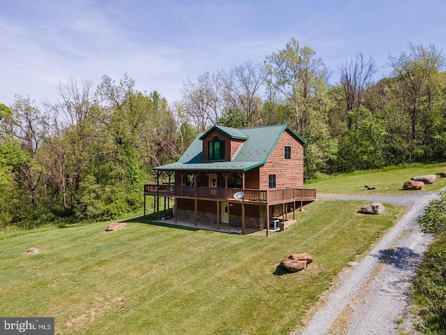 rear view of property with a wooden deck, stone siding, metal roof, a lawn, and driveway