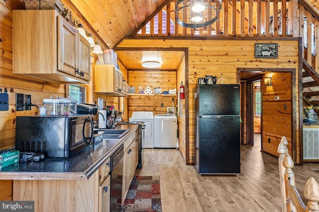 kitchen featuring wood walls, dark countertops, a sink, independent washer and dryer, and black appliances