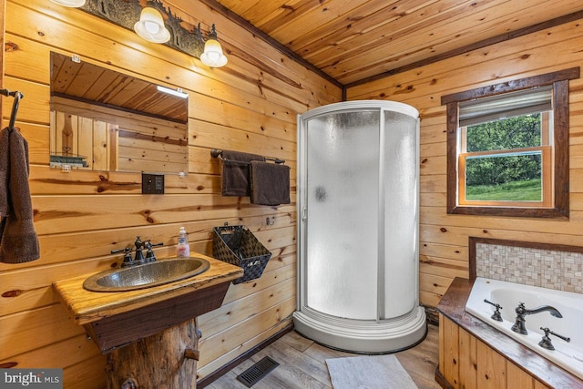 bathroom with wooden walls, a sink, a shower stall, wooden ceiling, and a garden tub