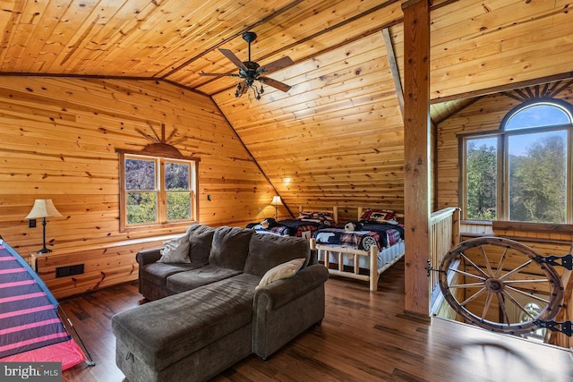 living area featuring ceiling fan, wood walls, vaulted ceiling, and a wealth of natural light
