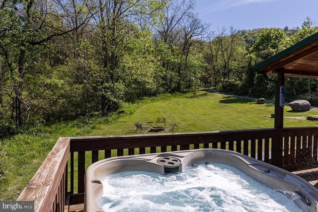 wooden terrace with a yard, a view of trees, and a hot tub
