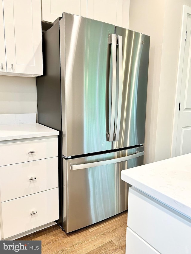 4655 Mountain Rd, Pasadena, MD 21122 - kitchen with freestanding refrigerator, white cabinets, light wood finished floors, and light stone countertops