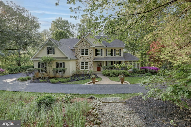 view of front of house featuring stone siding, stucco siding, and roof with shingles