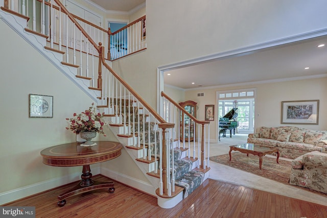 stairs featuring wood finished floors, baseboards, crown molding, and recessed lighting