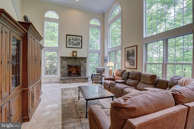 living room with light colored carpet, ornamental molding, a stone fireplace, and a high ceiling