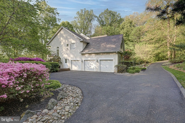 view of property exterior with stucco siding, driveway, a shingled roof, and an attached garage