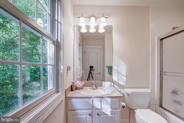 bathroom featuring toilet, a chandelier, vanity, and combined bath / shower with glass door