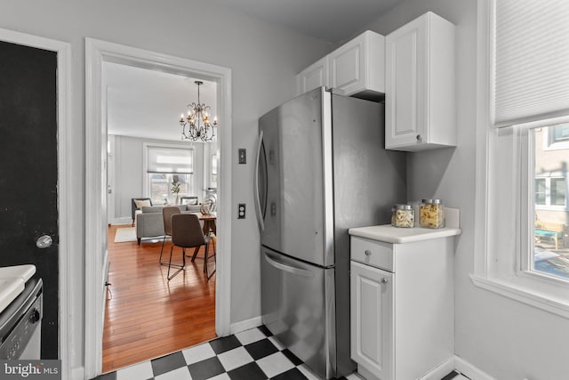 kitchen featuring white cabinets, tile patterned floors, an inviting chandelier, light countertops, and freestanding refrigerator