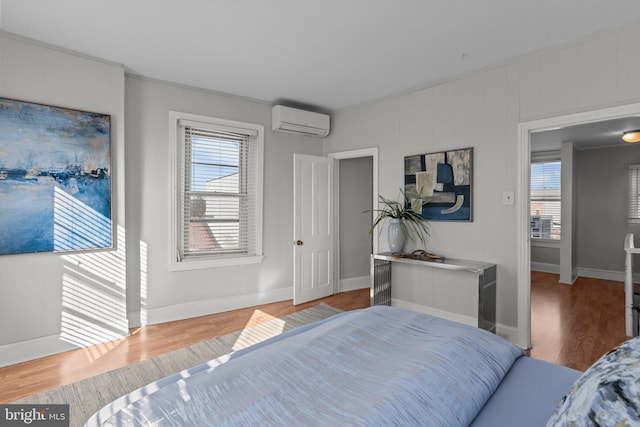 bedroom featuring baseboards, wood finished floors, and an AC wall unit