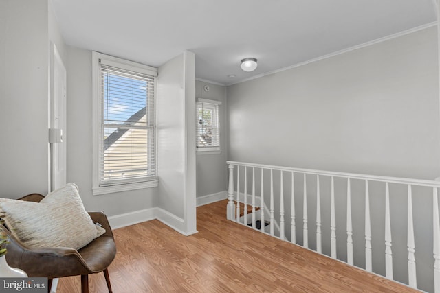 sitting room featuring wood finished floors, crown molding, baseboards, and an upstairs landing