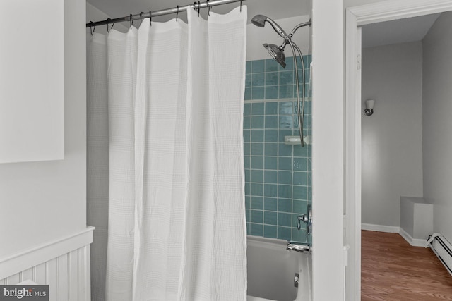 bathroom with a baseboard radiator, wood finished floors, shower / tub combo, and baseboards